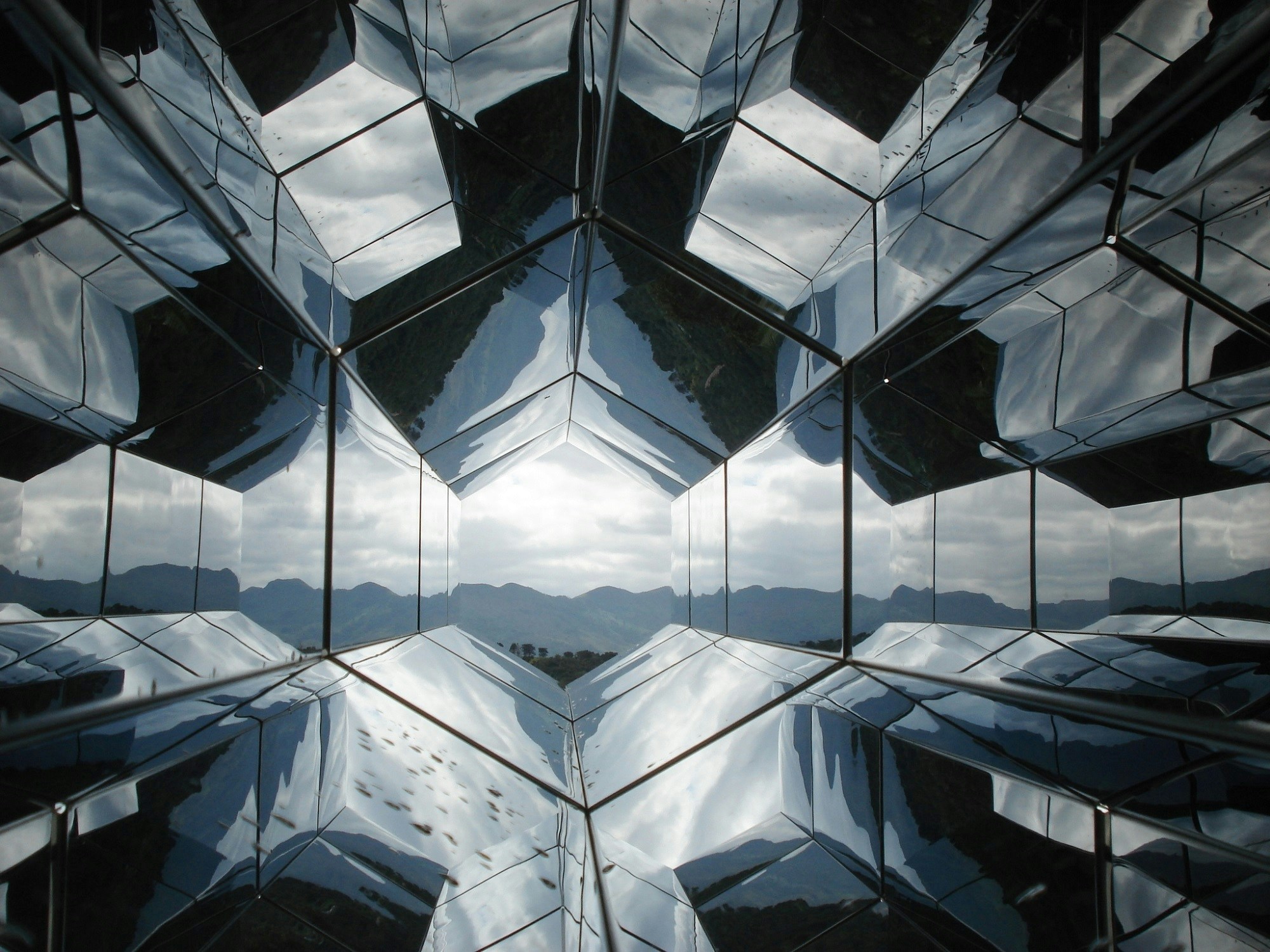 Geometric mirrored structure with mountains in the distance